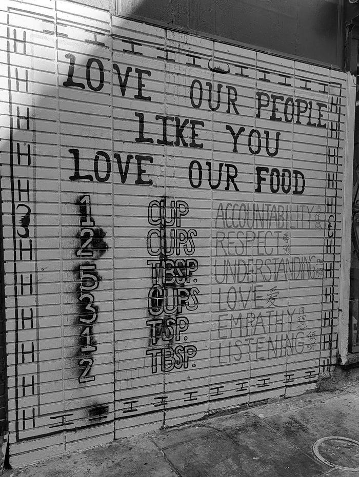 Mural on wall in alley in Chinatown, San Francisco. The heading is “Love Our People Like You Love Our Food.”