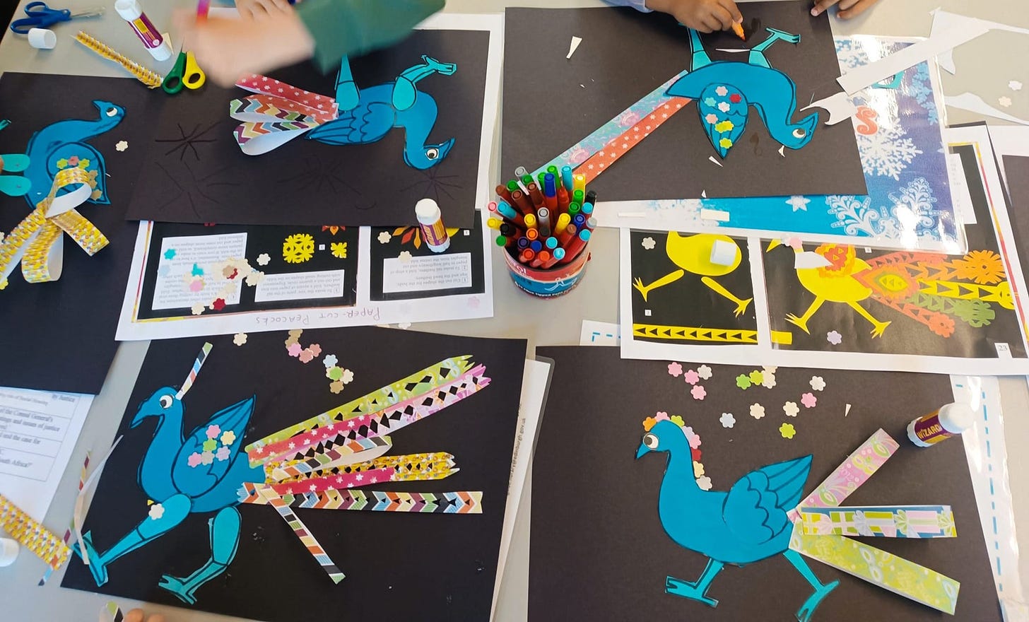 children making pictures of peacocks with colourful stickers and patterned paper