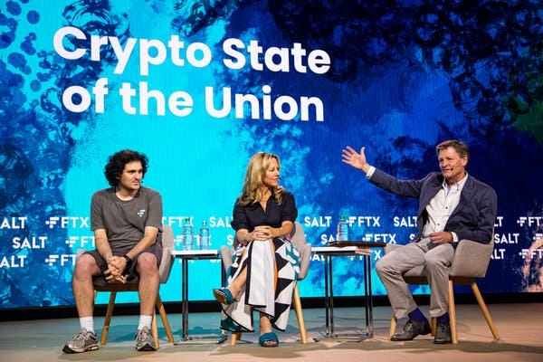 Sitting in chairs in front of a blueish-black background with the words “Cryto State of the Union” are Sam Bankman-Fried, Katie Haun, the CEO of Haun Ventures, and the author Michael Lewis. 