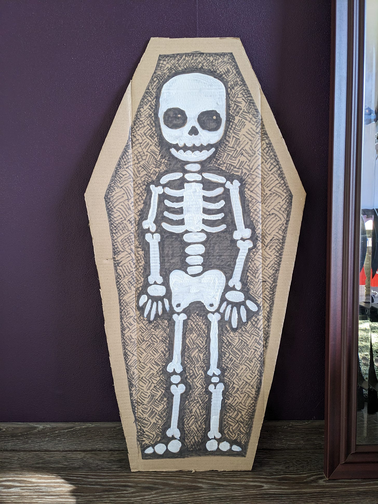 A cartoon skeleton drawn on a coffin-shaped piece of card