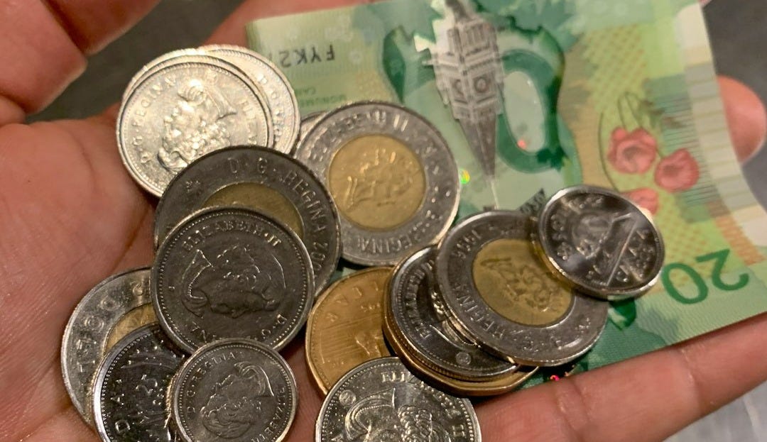 two-toned coins with banknote on hand two-toned coins with banknote on hand