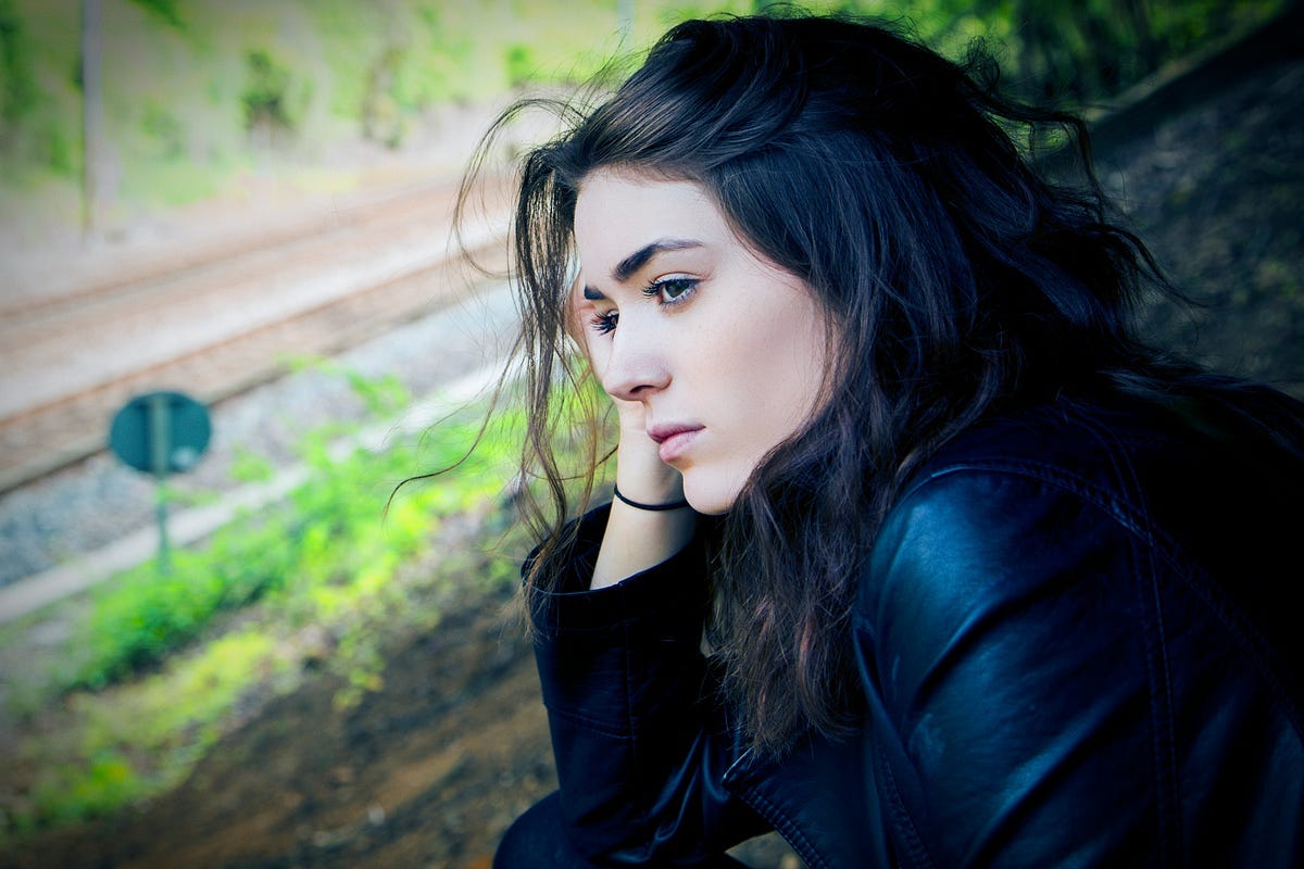 Sad girl looking down on rail track