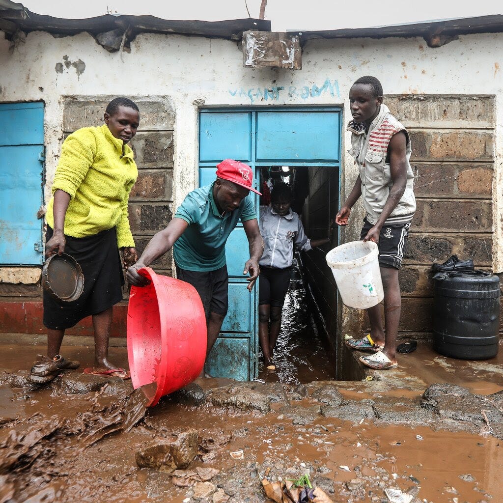 Residents use buckets to remove muddy water from their homes.