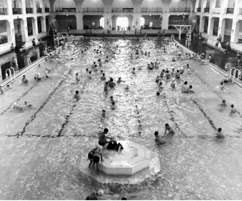 A large indoor swimming pool with people in it

AI-generated content may be incorrect.