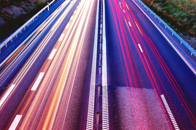 A colourful time lapse photo of a roadway showing traffic speeding along