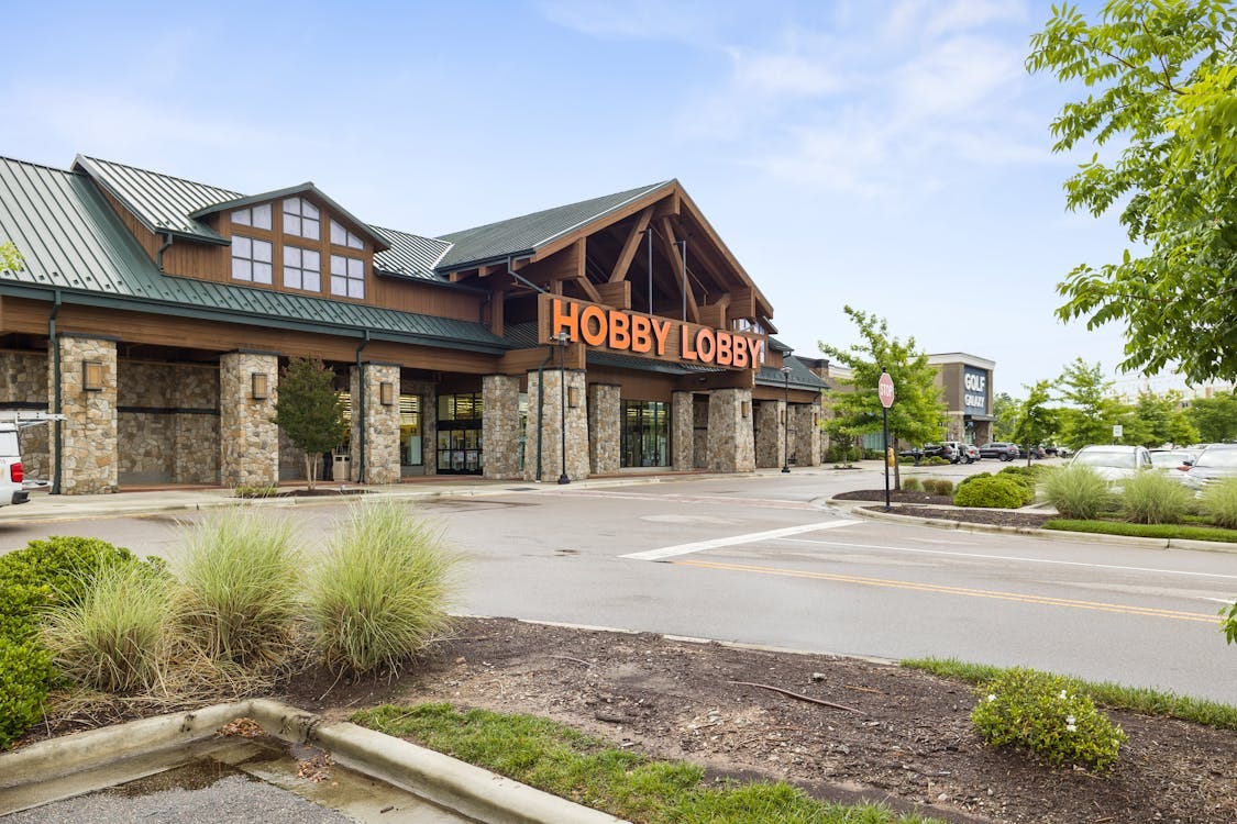 Free Front view of a Hobby Lobby store with clear blue sky and parking area. Stock Photo
