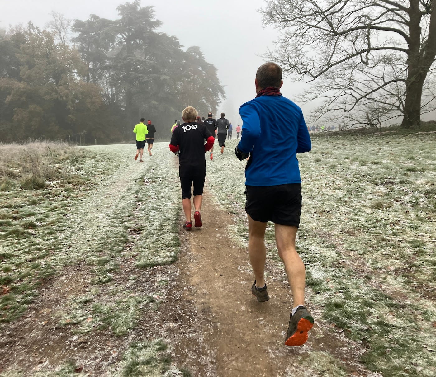 Runners heading into a misty horizon on hard ground topped with white frost