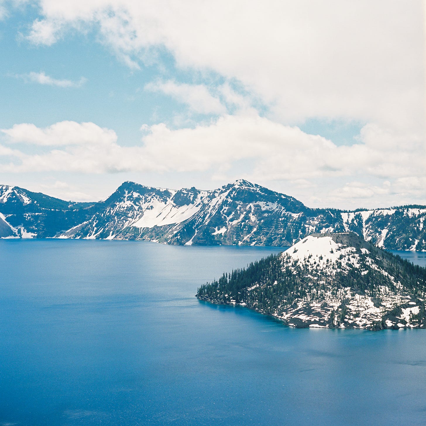 Photo of Crater Lake encircled by snowy mountains
