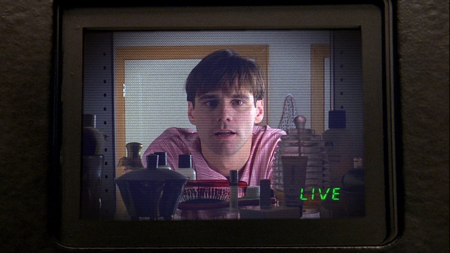 The Truman Show | Still features Jim Carrey as Truman Burbank staring into a hidden camera, displayed on another screen.