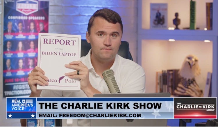 Screenshot of Charlie Kirk holding up a thick paperbound volume titled 'REPORT ON THE BIDEN LAPTOP' on his internet TV show, In the background is a truly ugly US flag/eagle head sculpture being used as a bookstop