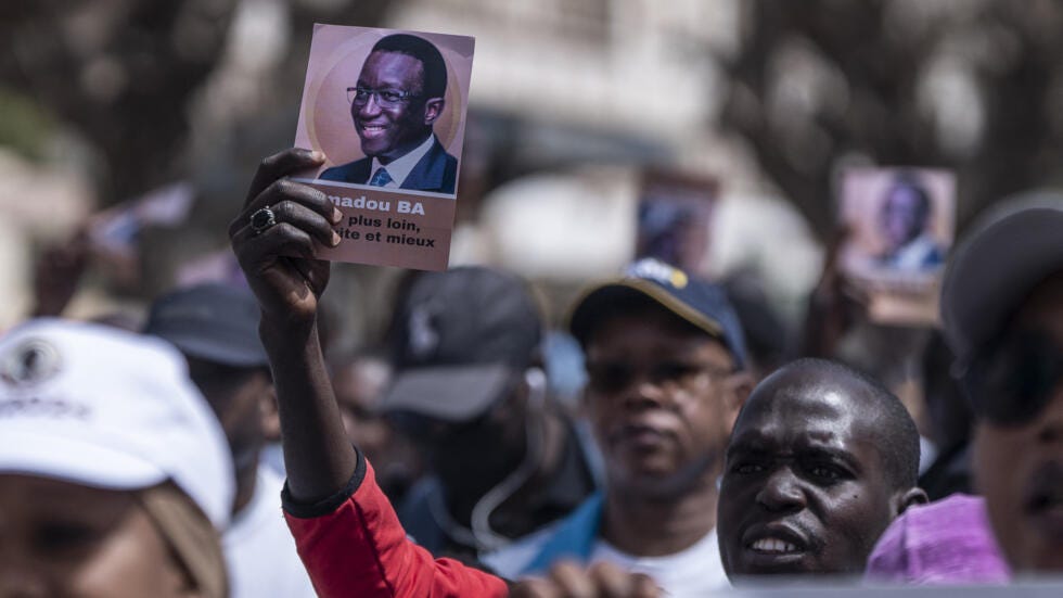 Supporters of the President of Senegal Macky Sall and presidential candidate Amadou Ba hold flyers carrying his portrait during a march for peace in Dakar on 3 March, 2024.