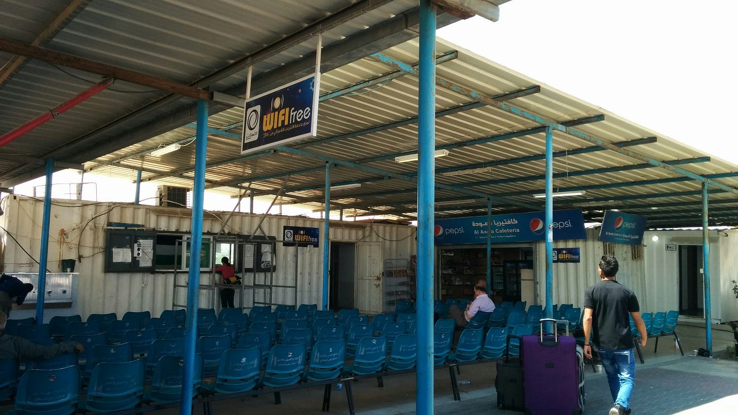 Several dozen blue chairs stand below corrugated metal roofing, and a sign above advertises Free Wifi