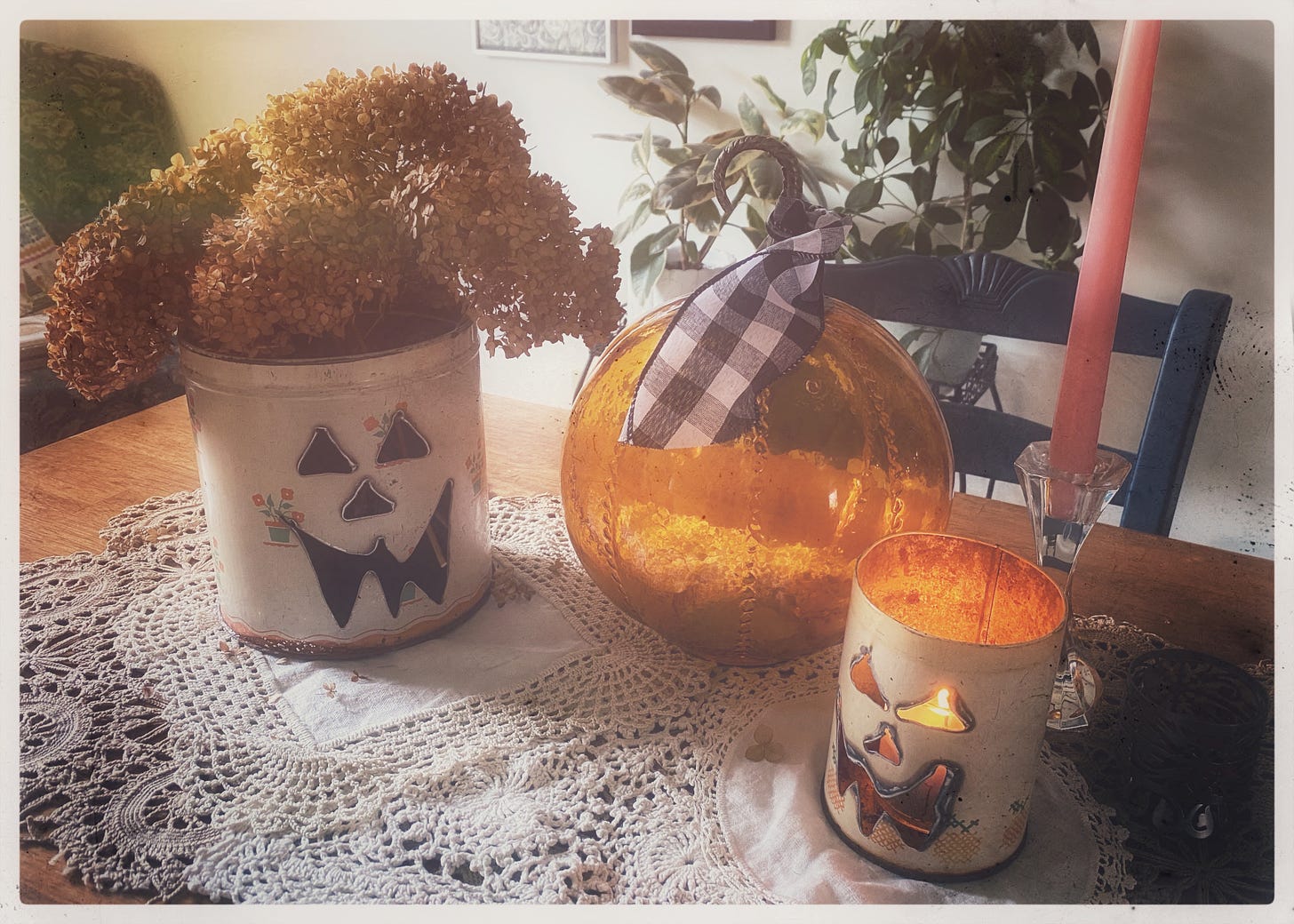 photo of a festive decorate table, including a glass pumpkin, jack o lantern canisters, and vintage doilies.