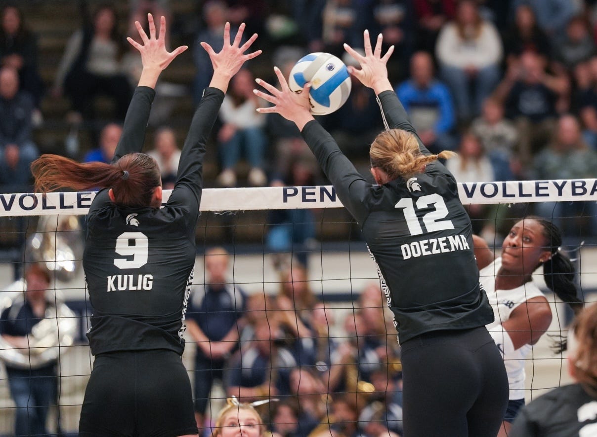 two volleyball players blocking an attack