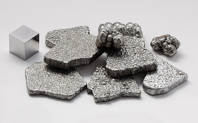Different forms of iron: a shiny cube, pitted amorphous flat shapes of silver, and collections of iron 'bubbles'.