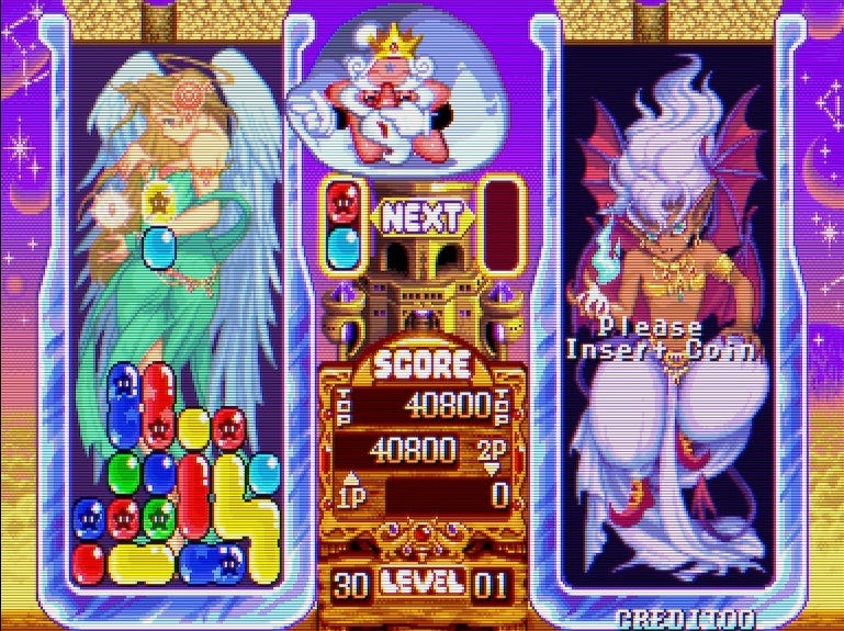 A screenshot from Pnickies' single-player mode, with an angel dressed in a green down, wings and halo visible, is in the background of 1P's playing area. A devil is in the background of 2P's area, which is otherwise blank. In the middle, an anthropomorphic star with a crown and a beard directs Pnickies to fall into the playing areas.