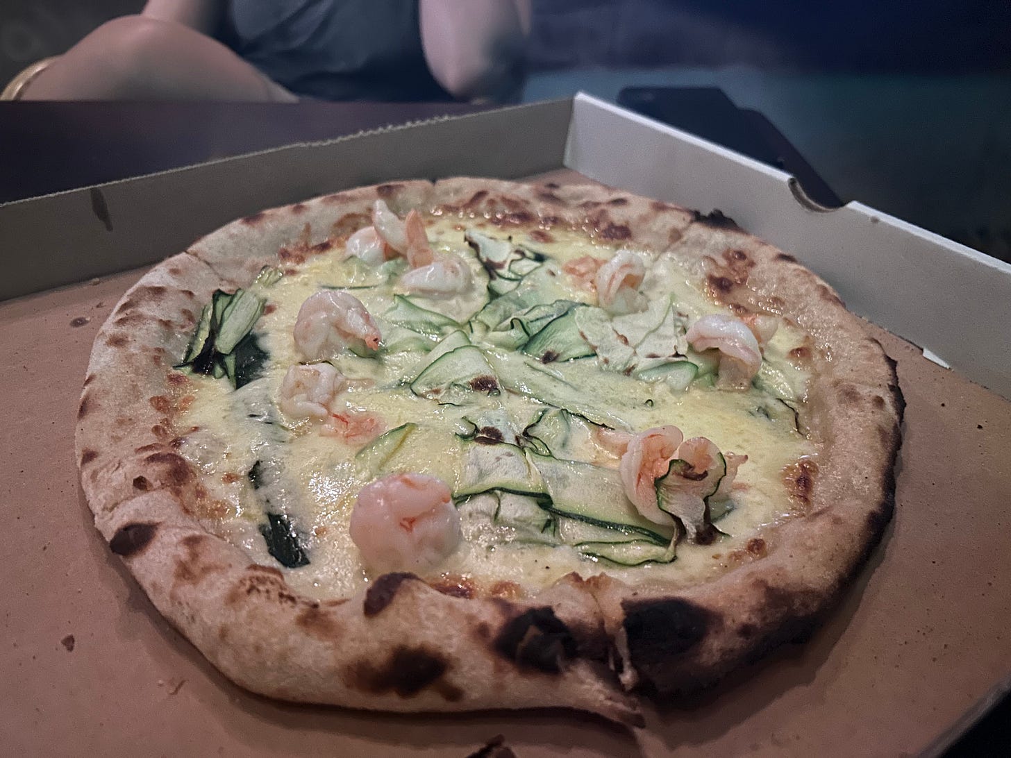 Pizza topped with cheese, prawns and shaved zucchini.