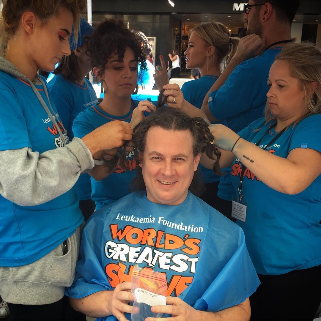 A man with mid-length hair having it cut off for charity.