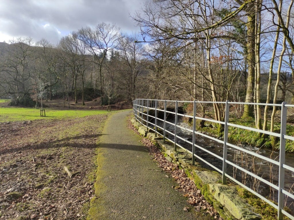 Path at the top end of the park with thin metal railings keeping us off the river on the right.