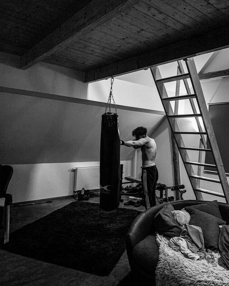 This may contain: a man standing next to a punching bag in a living room under a loft ladder
