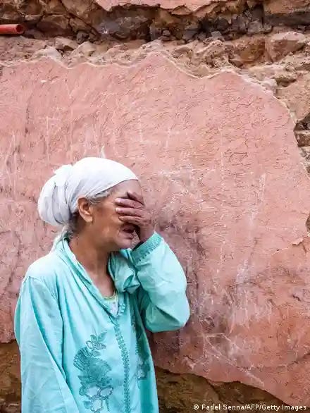 A woman crying in front of her earthquake-damaged house