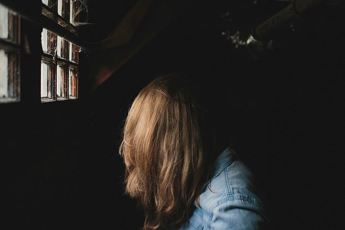 teenage girl facing away in a dark dungeon-like room depicting despair teenage girl facing away in a dark dungeon-like room depicting despair