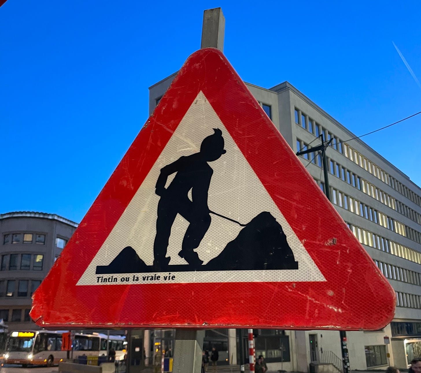 A triangular roadwork sign featuring Tintin with a shovel in silouette.