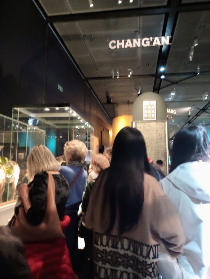 Crowds in high-ceilinged exhibit space, with black walls, and Changan in large letters hanging from celing