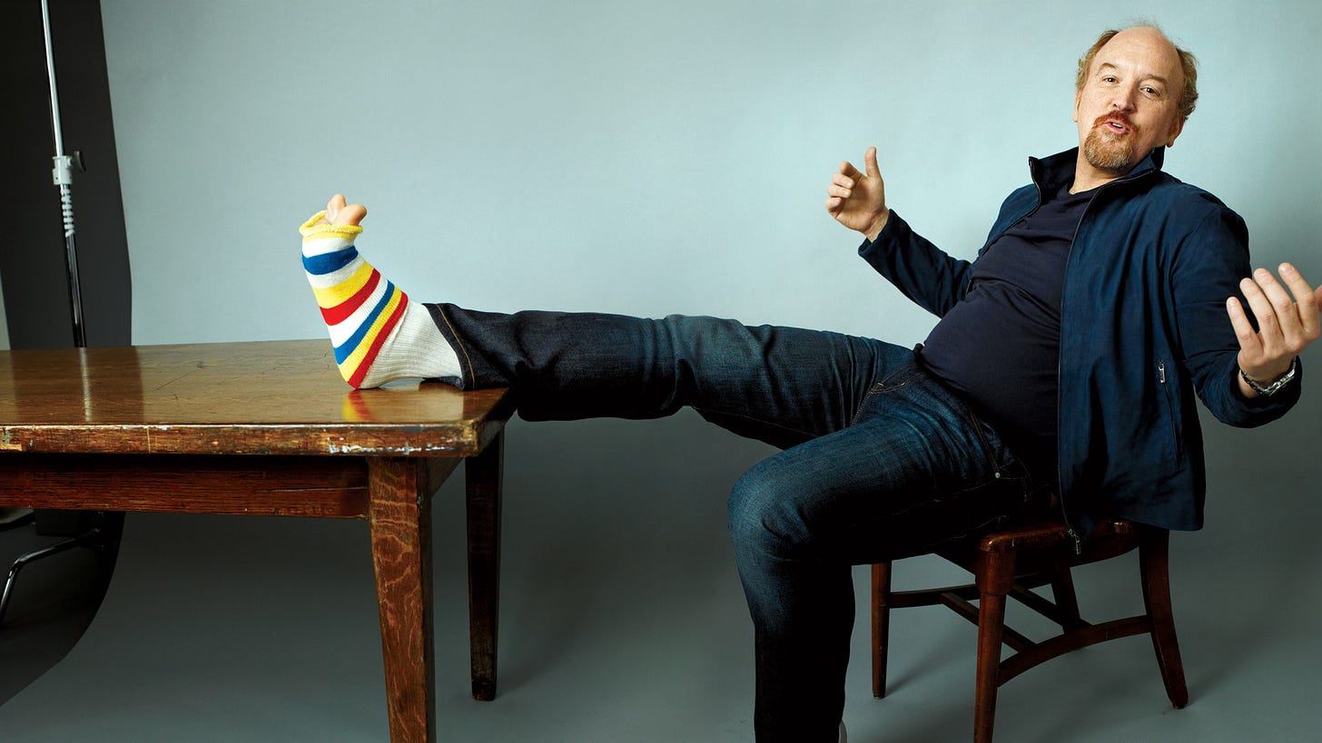 This image may contain Louis C.K. Clothing Apparel Footwear Shoe Human Person Sitting Furniture and Chair