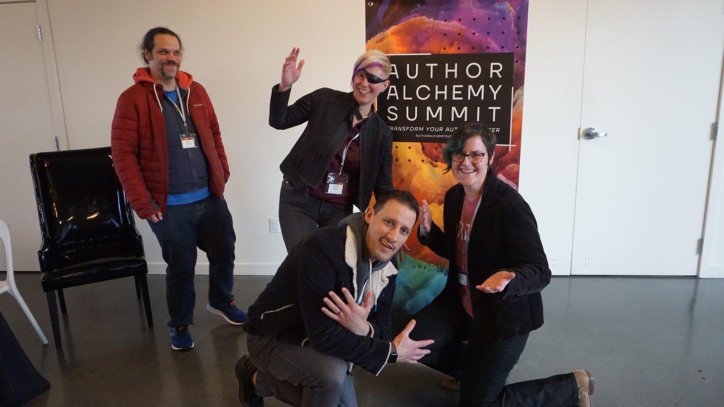 People posing in front of the Author Alchemy Summit banner
