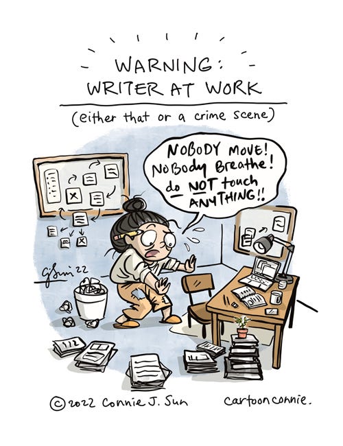 Warning: Writer at Work Single-panel comic illustration of a cartoon girl with a messy bun, tackling a writing deadline. Heading reads, "Warning: Writer at Work." In parentheses: "either that or a crime scene." The girl is standing in the middle of a room, with piles of papers and reference materials all over the floor, post-its affixed to the walls, bulletin boards, and a desk cluttered with a laptop, notebook, and mugs. She is in a state of dramatic, high-functioning, near-panic and exclaims loudly to no one, "NOBODY MOVE! Nobody breathe! Do not touch ANYTHING!!" Illustration by Connie Sun, cartoonconnie, 2022.