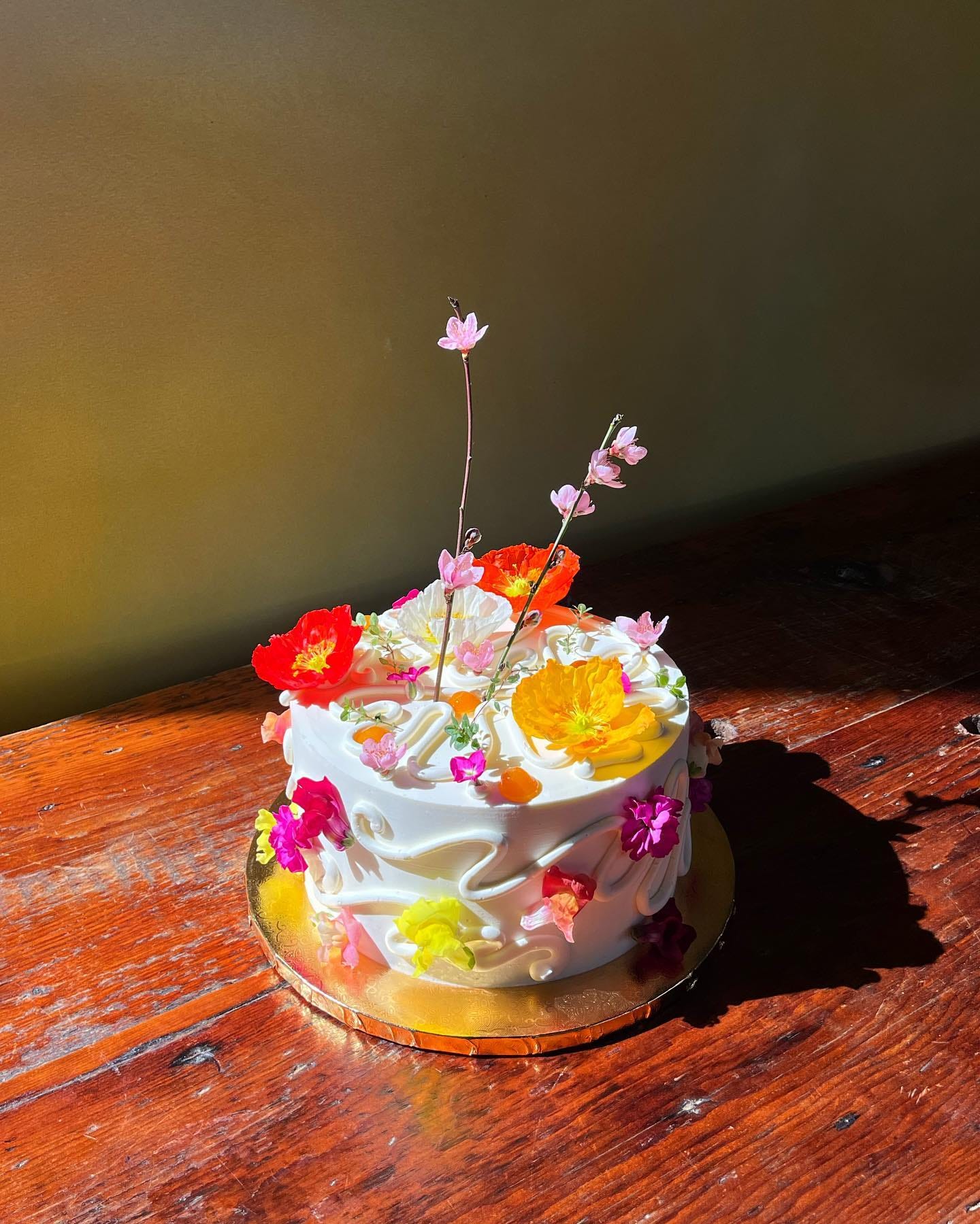 a bright cake covered in flowers and sprigs