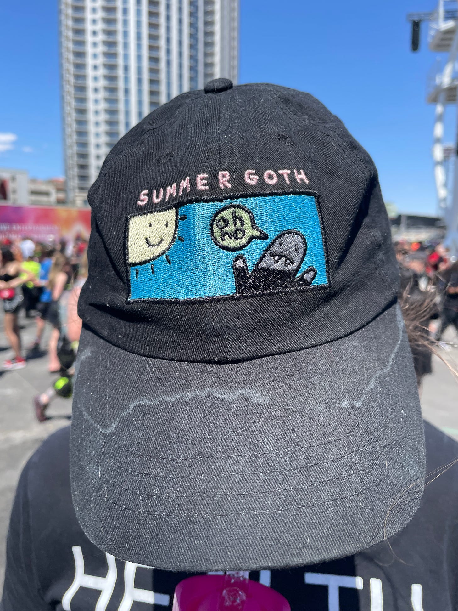 A baseball cap of a single-panel comic of a goth in the sun saying "Oh no". The panel is titled "Summer Goth"