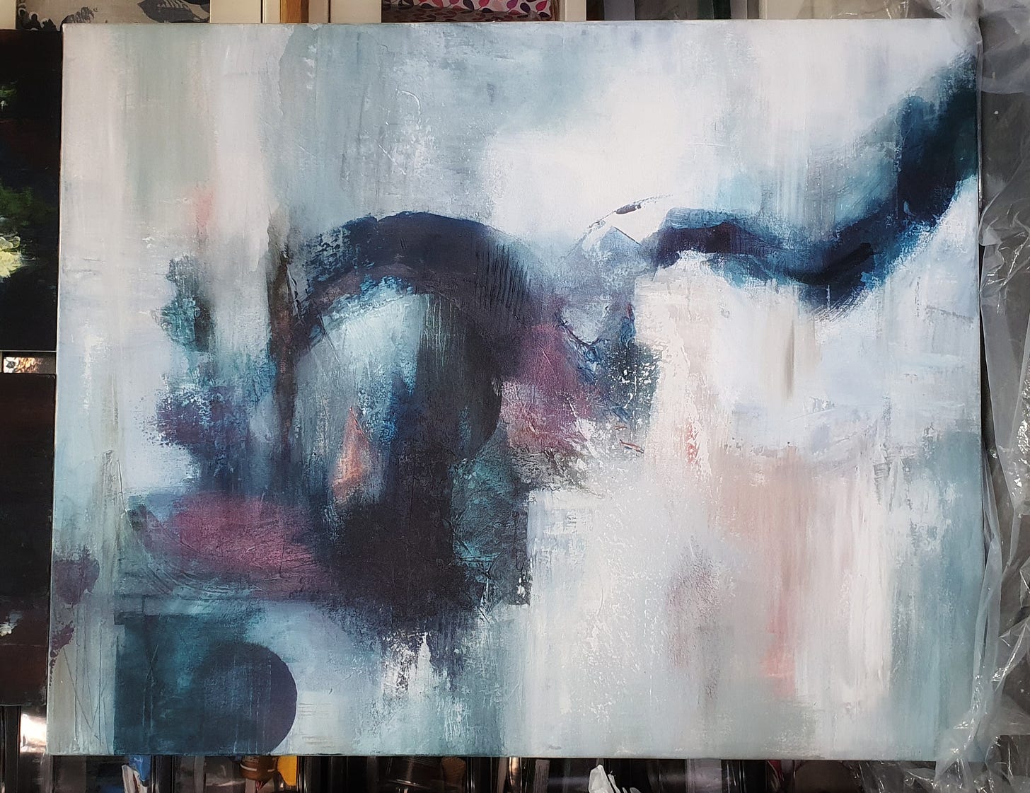 Gratitude in the form of a large abstract painting by Susan Mills Art. it is a large dark swirl of dark indigos prussians and iridescent mauves on a paler background 