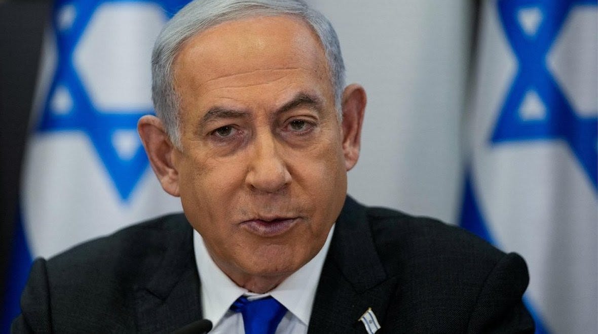 Close up picture of Benjamin Netanyahu speaking with Israeli flags on the background