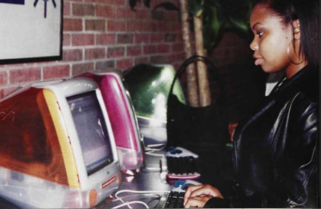 Black woman in leather jacket using a orange PC.