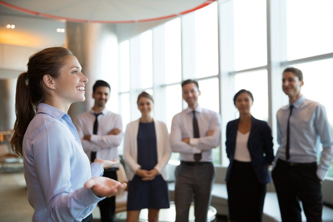 Female executive manager and team standing in front of high glass windows