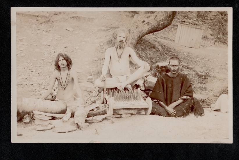 image: vintage postcard image of an Indian yogi sitting on a bed of nails surrounded by two other sadhus