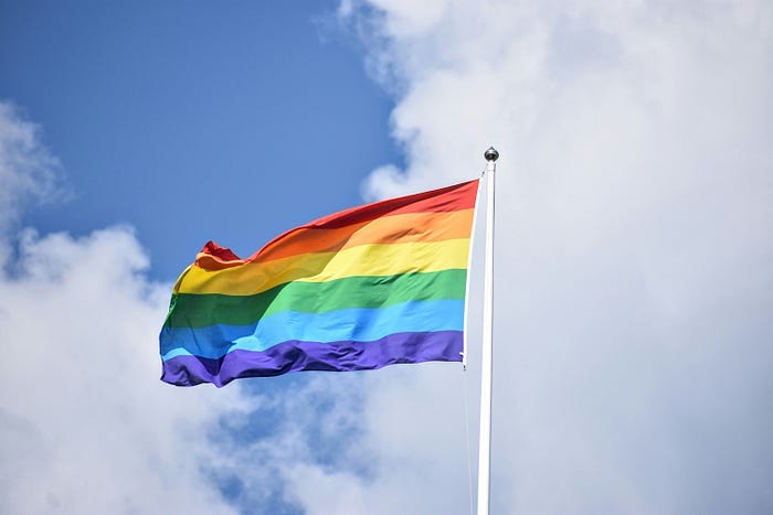 A Pride flag, blowing in a stiff wind. A Pride flag, blowing in a stiff wind.