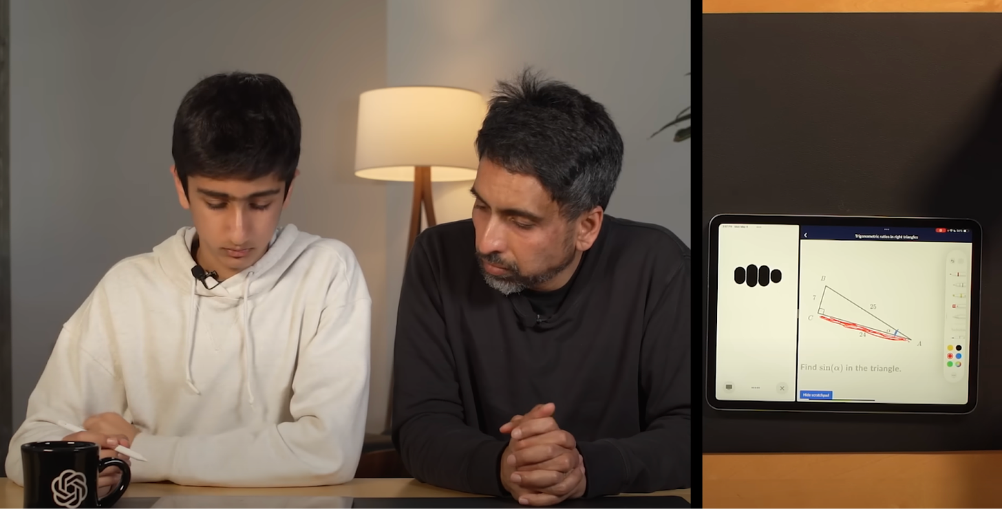 Sal Khan and his son Imran sit in front of a table that has a Khan Academy exercise on it about finding the sine ratio of an angle in a right triangle.