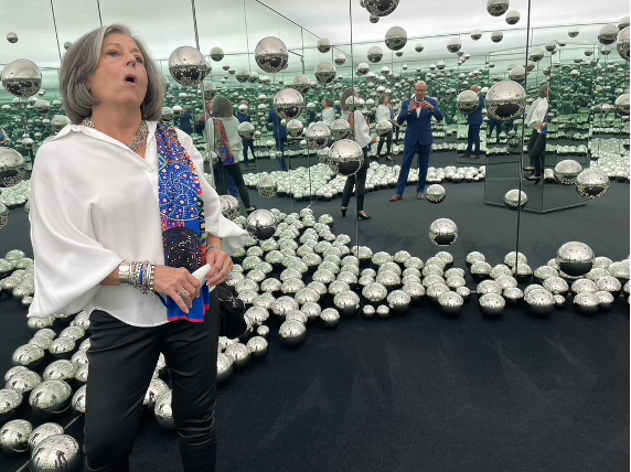 A person standing in front of a mirror with many silver balls

Description automatically generated
