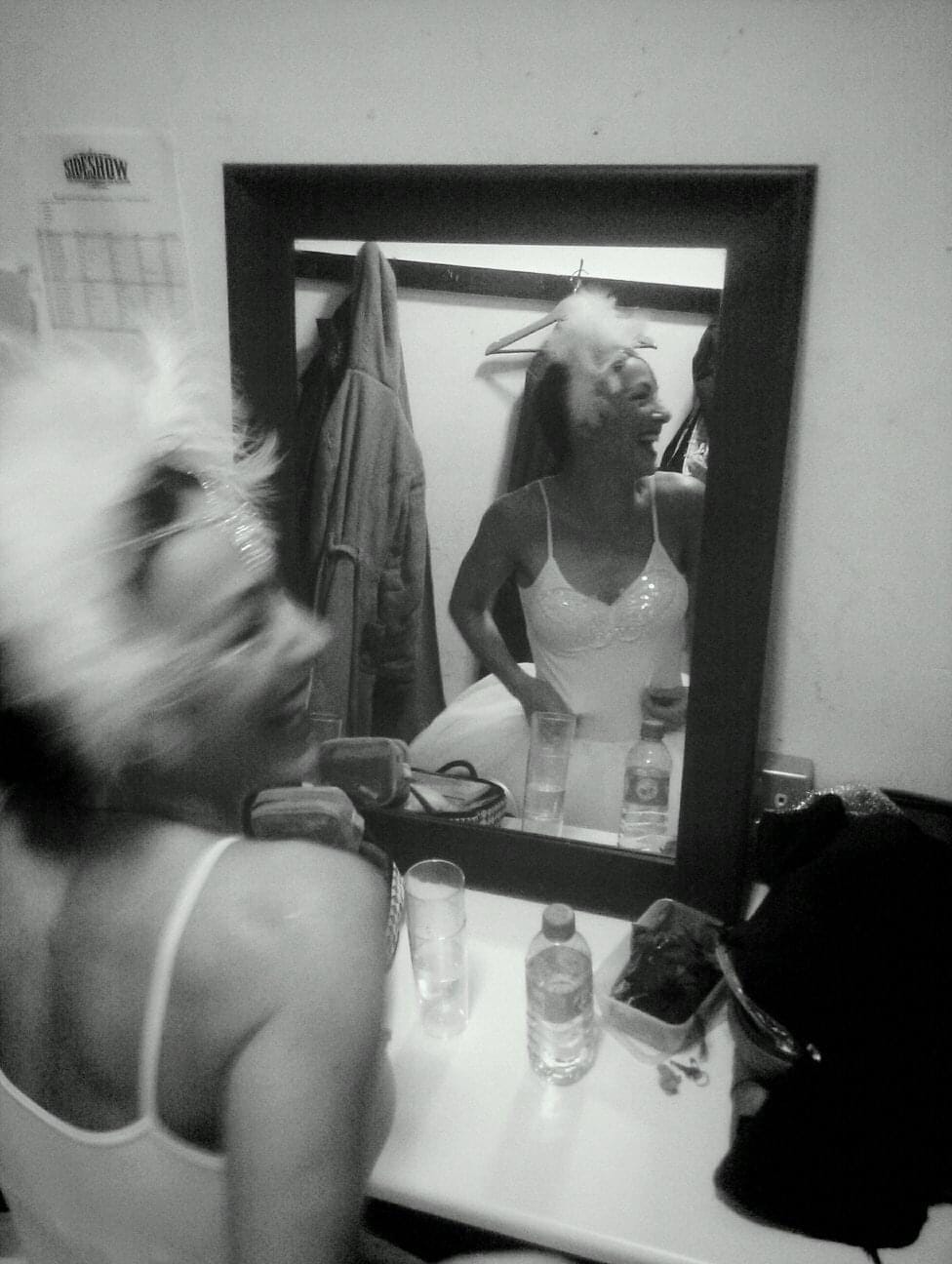 A feathered performer looking at herself in the mirror