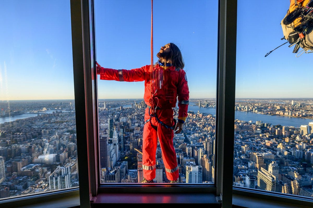 jared leto outside the empire state building in an orange jumpsuit