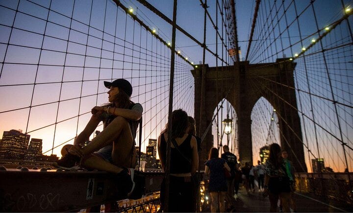 Walkers explore Brooklyn Bridge at dusk.