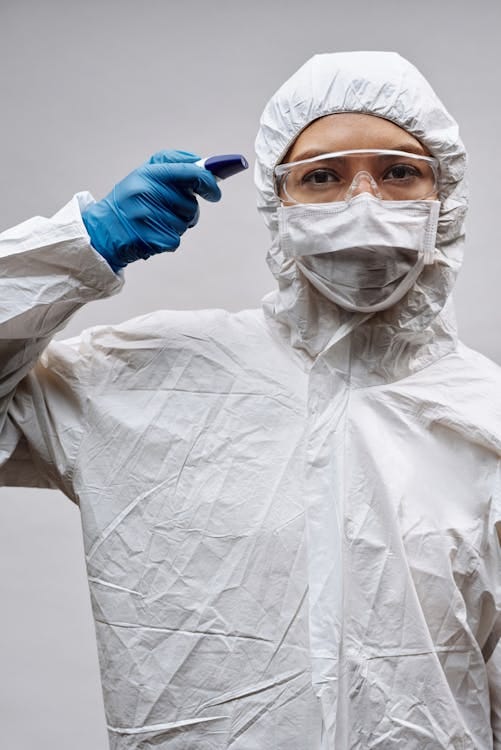 Free Healthcare worker wearing PPE and holding a thermometer. Stock Photo