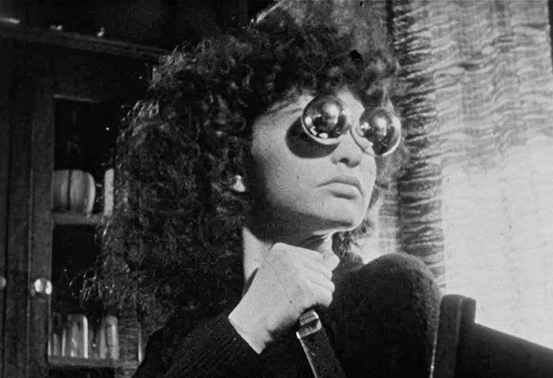 Maya Deren, avant-garde filmmaker, holding a knife in a menacing way and wearing glasses that look like glass globes