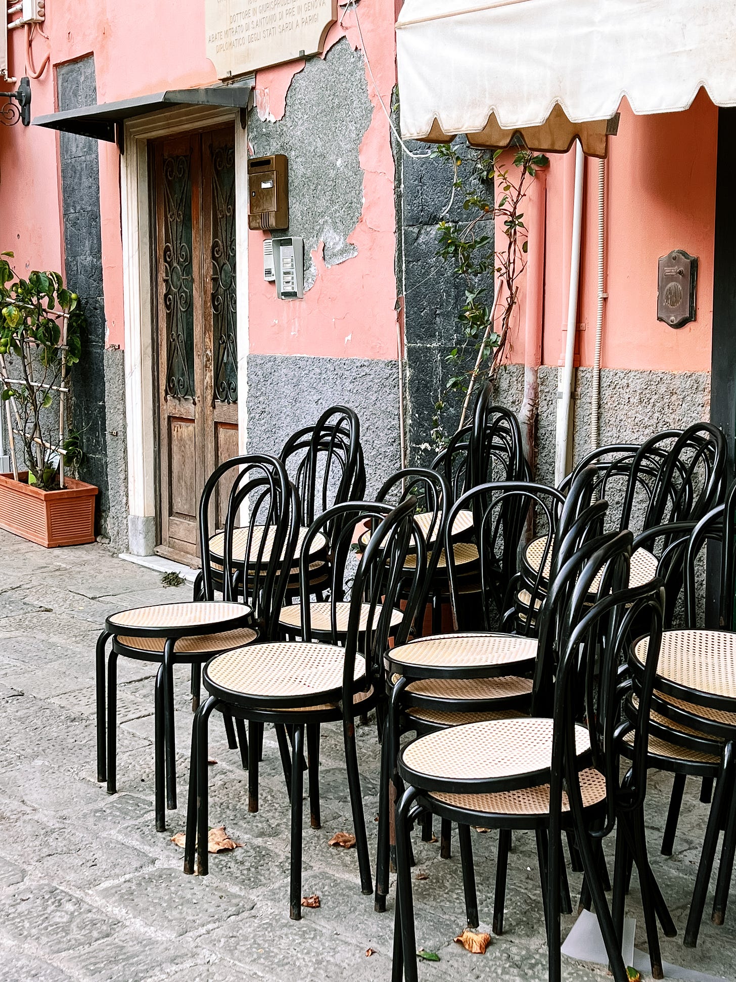 Cafe chairs stacked outside of a pink building in Monterosso al Mare