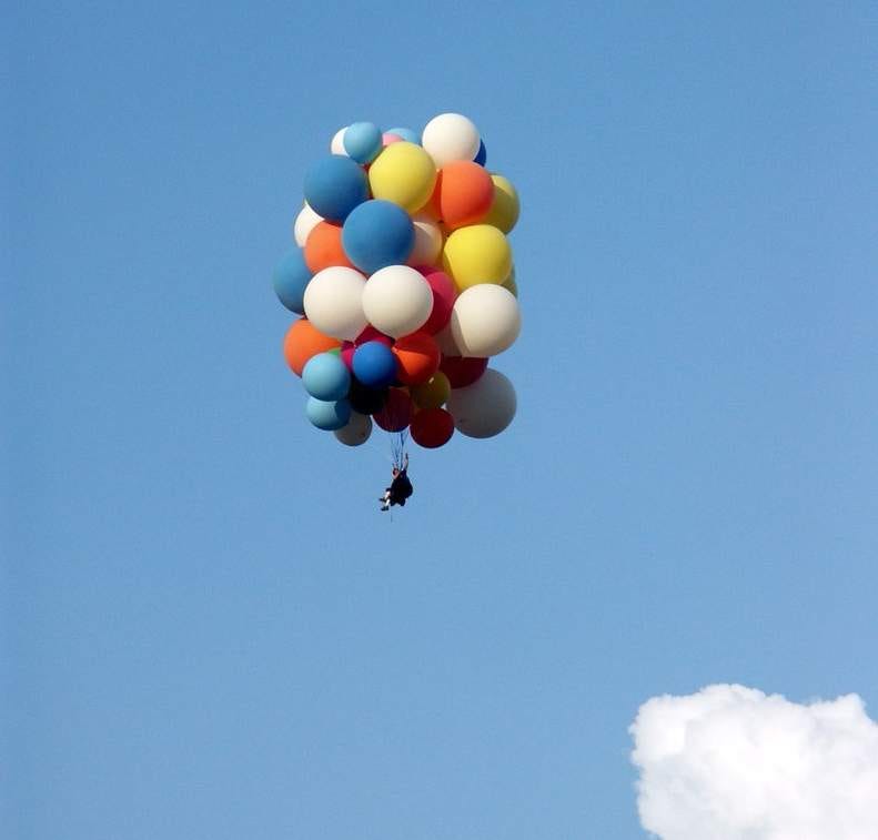 A so-called "cluster ballooner" - someone using dozens of balloons to suspend themselves in the air.