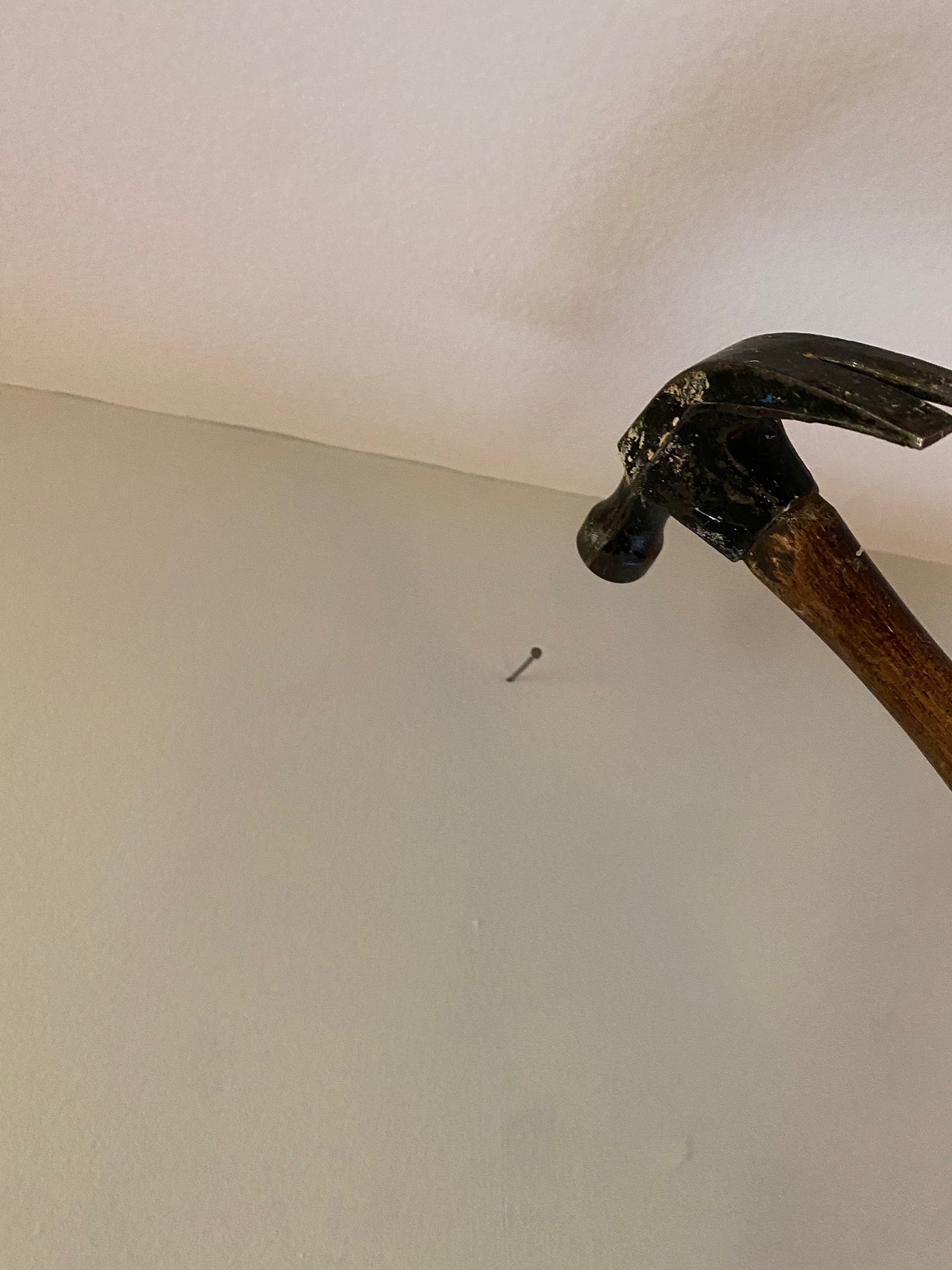 Tacking a nail into the wall to hold the crown molding while we put it up.