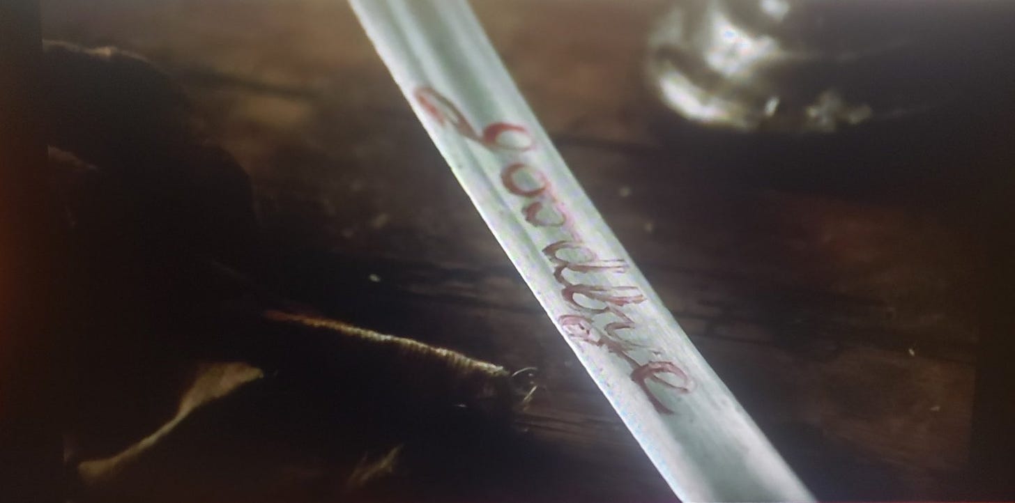 Still from the movie The Duellists. The word "goodbye" is written on a sword in red lipstick
